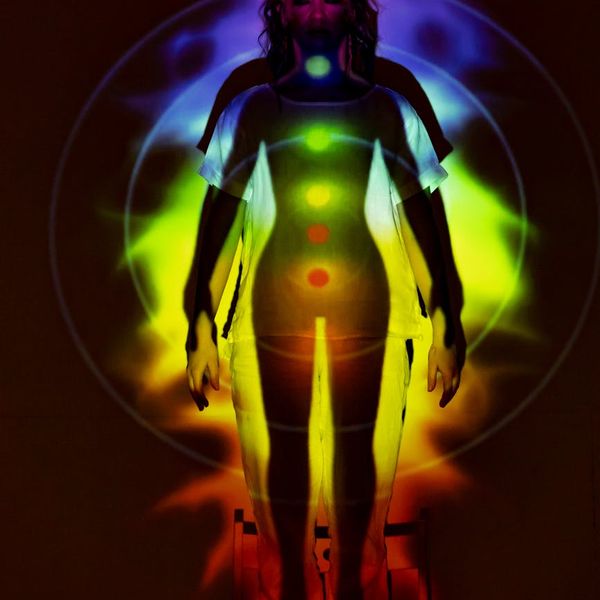 Silhouette of a person in a yoga pose against a mint-colored light.